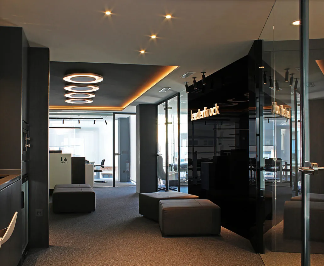 Acceso a las oficinas de Leaderbrock con el logotipo sobre panel negro y mamparas de cristal en Valencia